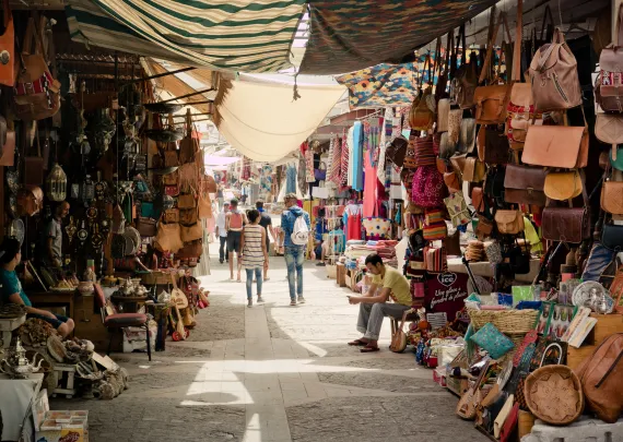 A bustling scene at a traditional souk with colorful stalls and crowds of people exploring various goods.