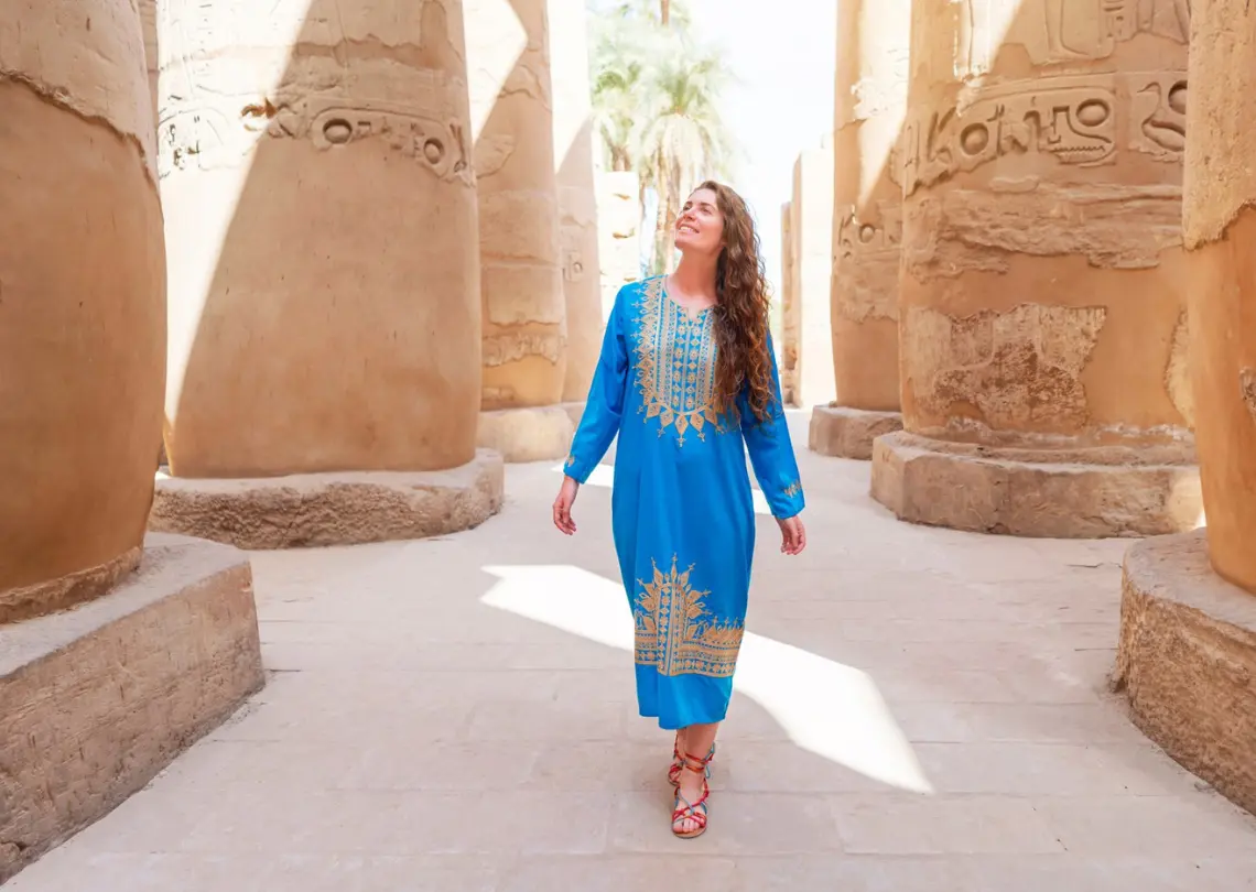 A woman dressed in traditional Egyptian attire, standing in front of an ancient monument, showcasing the rich cultural heritage of Egypt