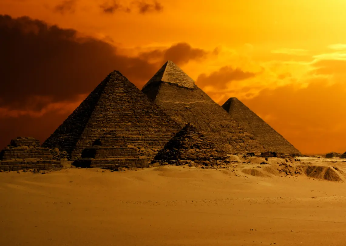 A majestic pyramid in Egypt, standing tall against the backdrop of a desert landscape and a orange sky